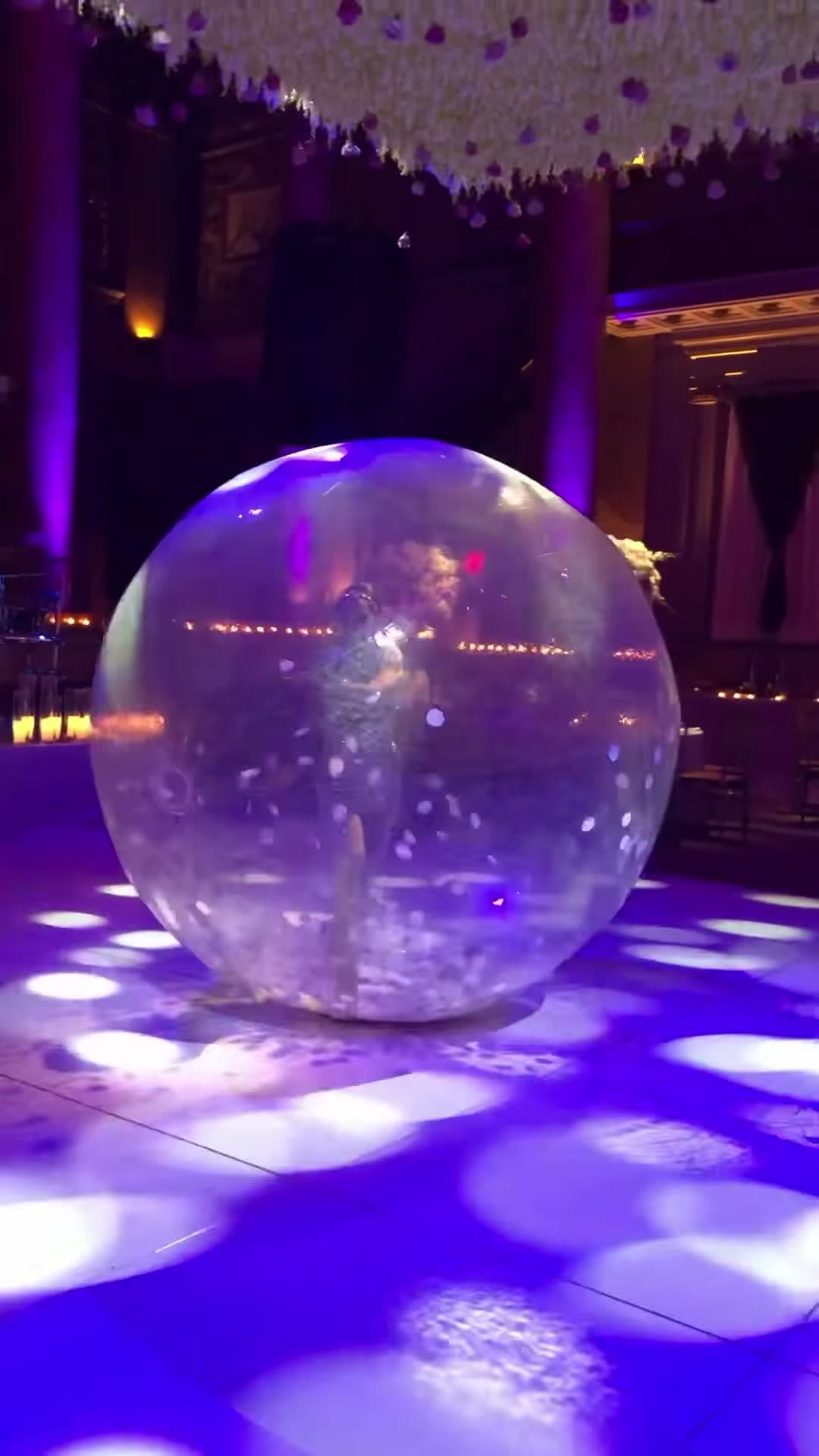 Acrobat performer inside transparent inflatable bubble at a ballroom event in New York