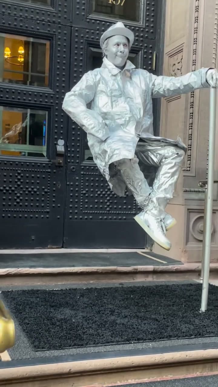 Levitating man street performer in silver suit floating mid air outside a New York City venue