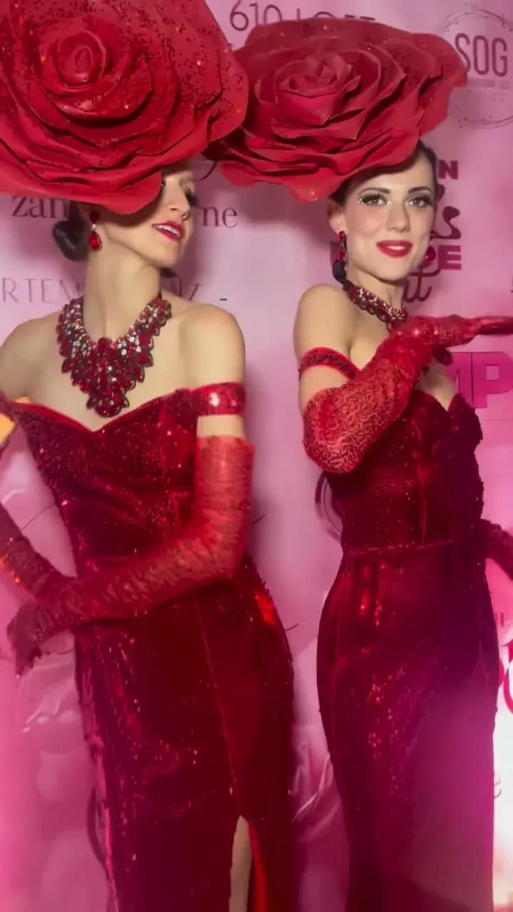 Two performers in red sequin gowns and oversized red rose headpieces, the Rouge Roses living decor act at a luxury event