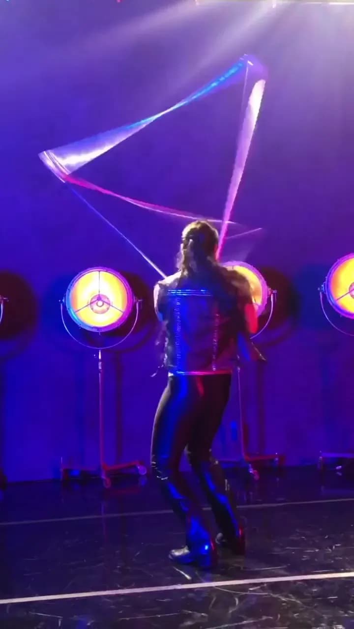 Spinning cube acrobat performing with a transparent prop under colored stage lights at a luxury event
