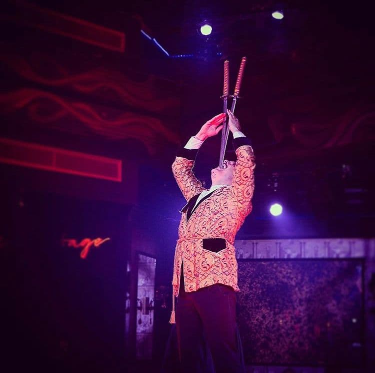 Sword swallower performing a sideshow stunt at a luxury circus themed event