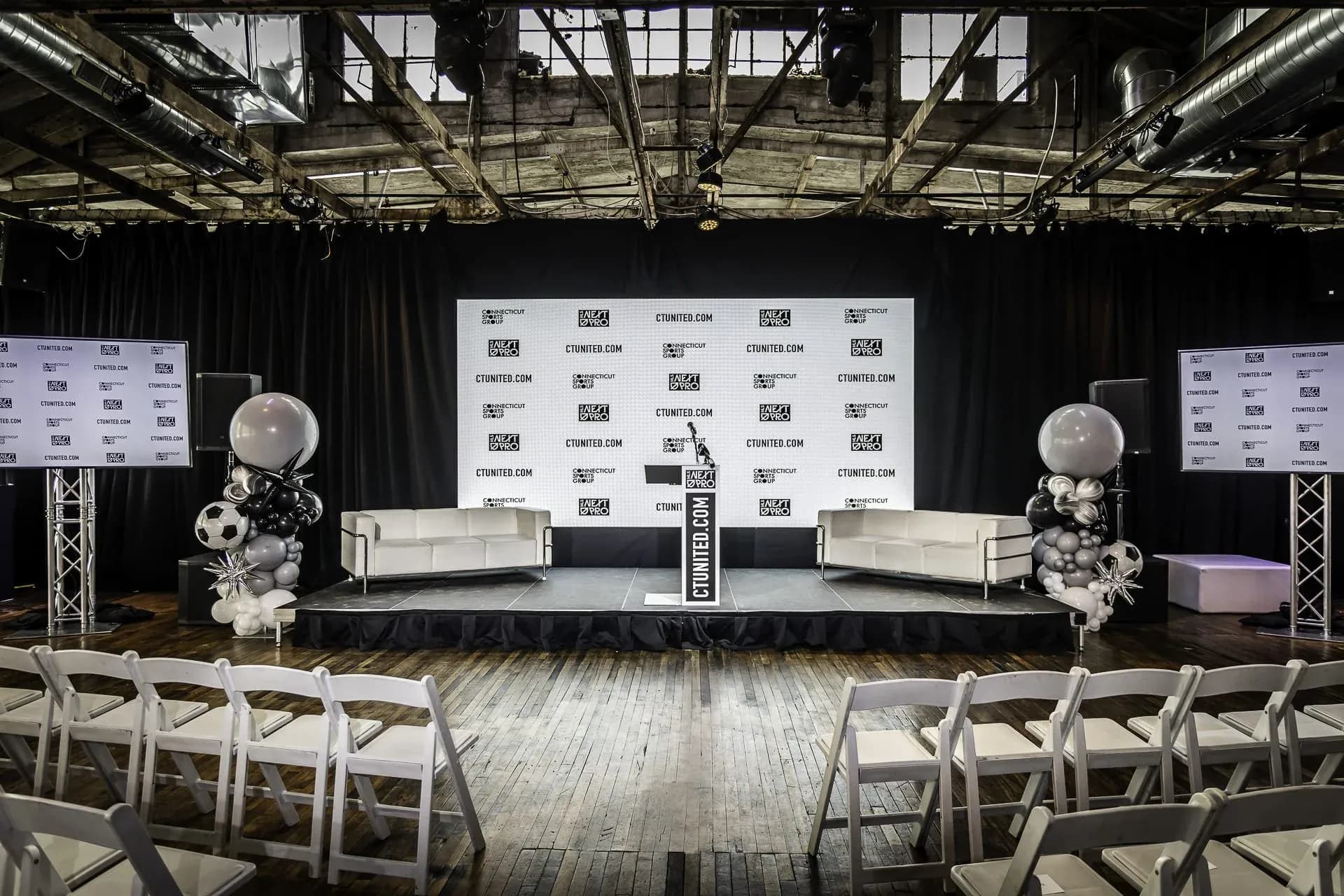 Branded press-conference stage with LED screens and podium. Venue: The Knowlton