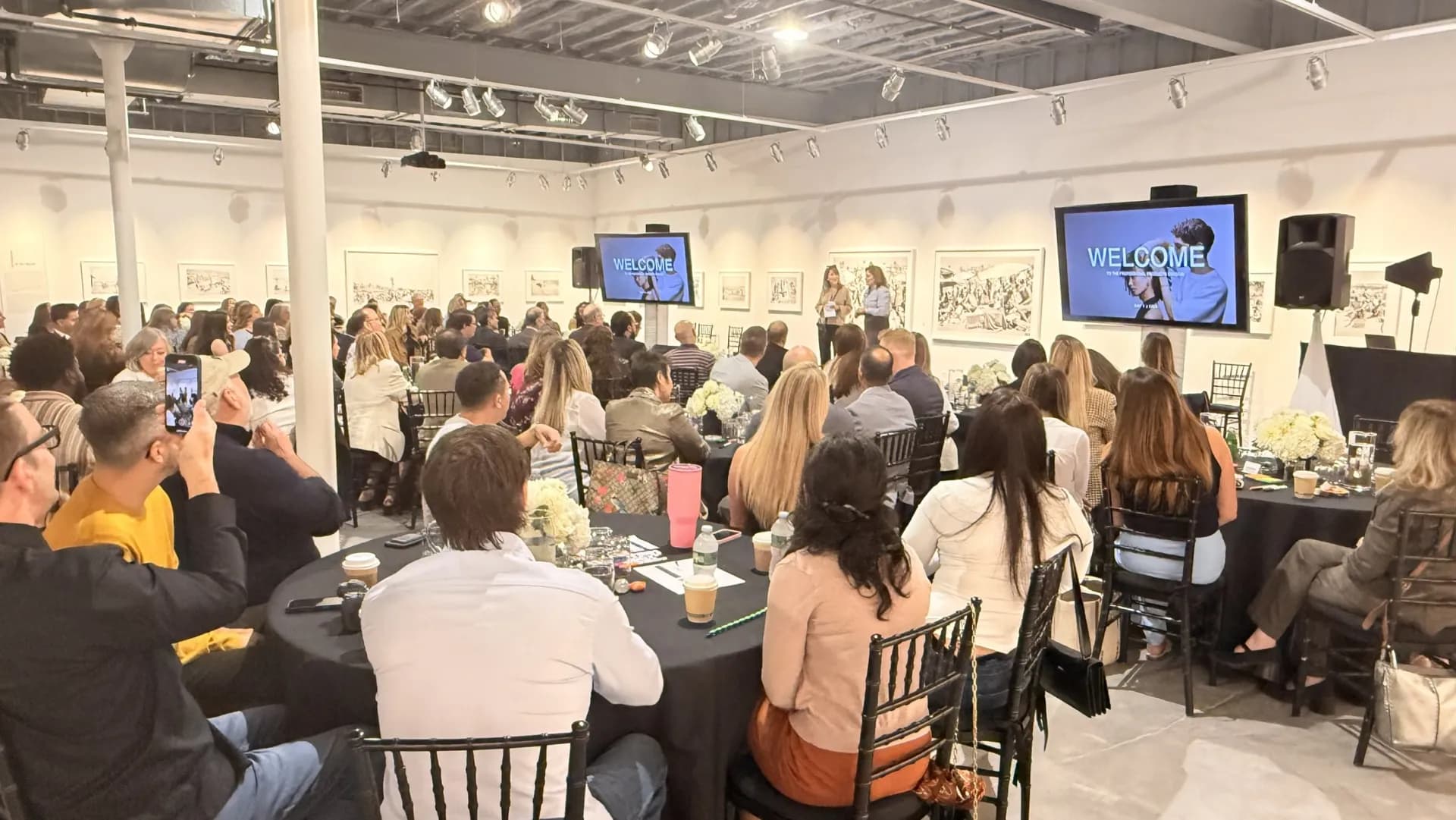 Dual welcome screens at a corporate breakfast in a gallery space