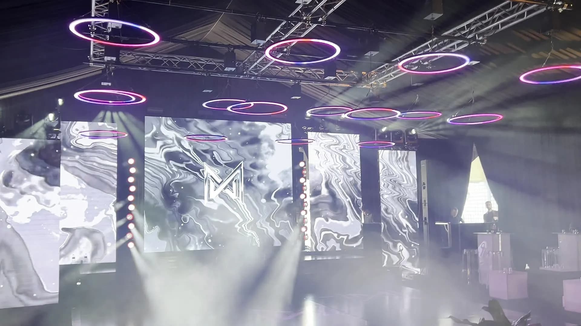 LED ring fixtures and motion-graphic video walls with haze beams at a party produced by Nicholson Events