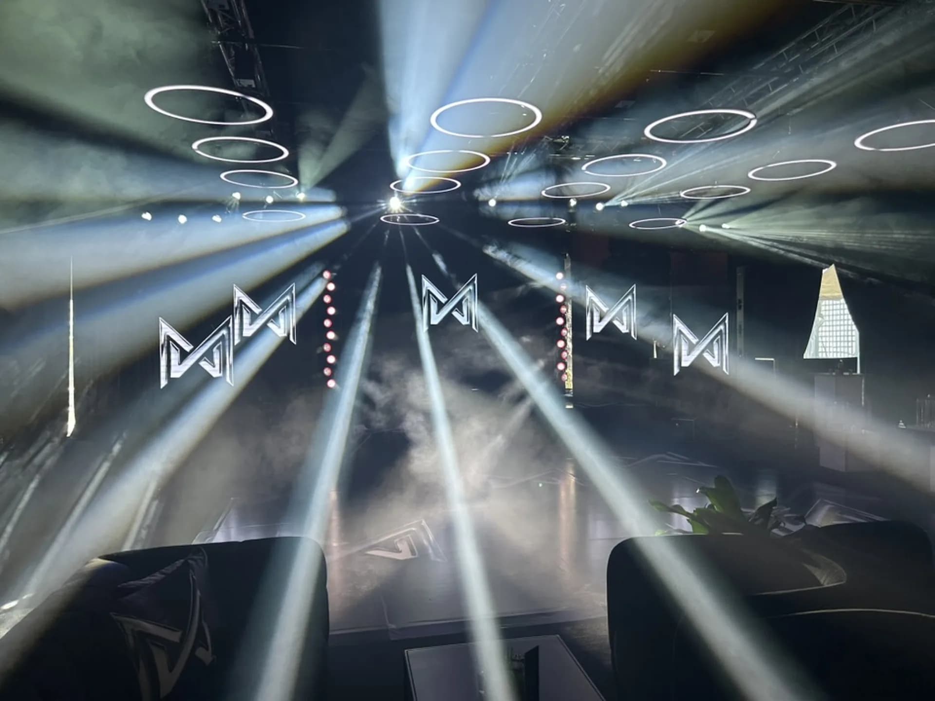 Ring lighting fixtures and converging white beams over a corporate event space produced by Nicholson Events