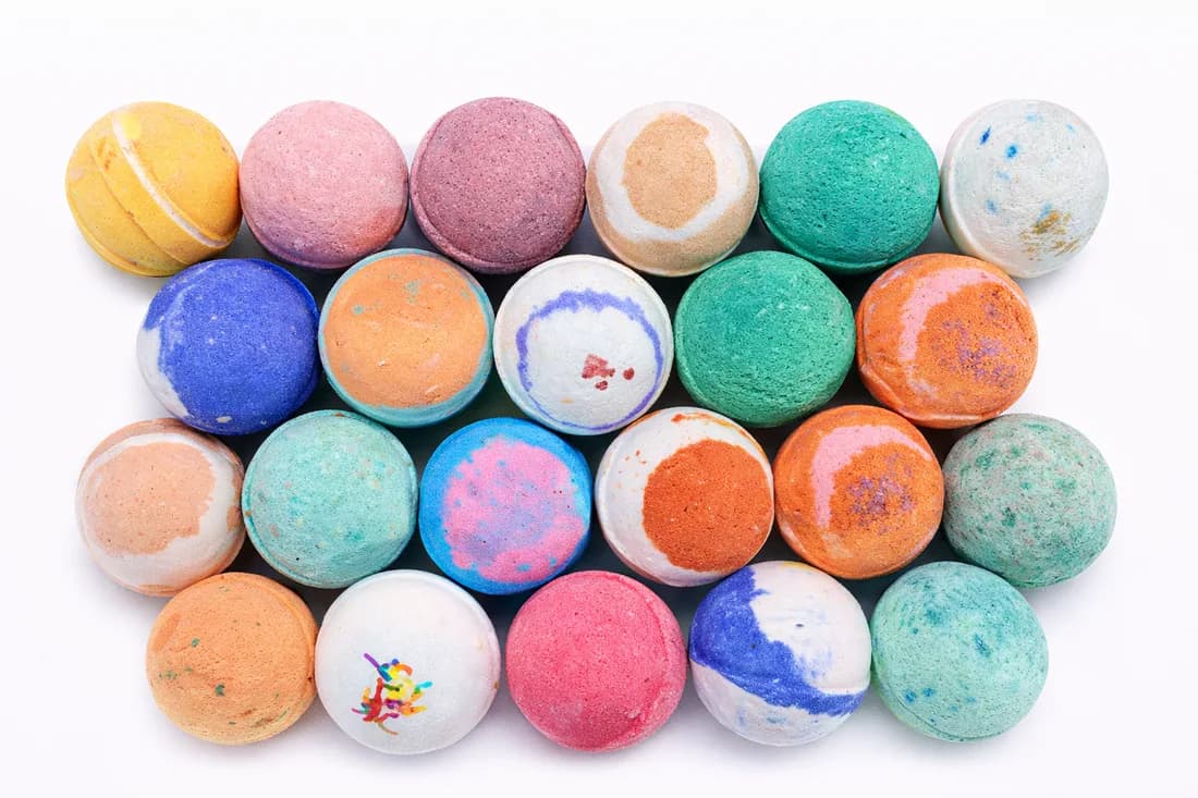 Overhead view of assorted colorful finished bath bombs arranged in rows at an event bath bomb station