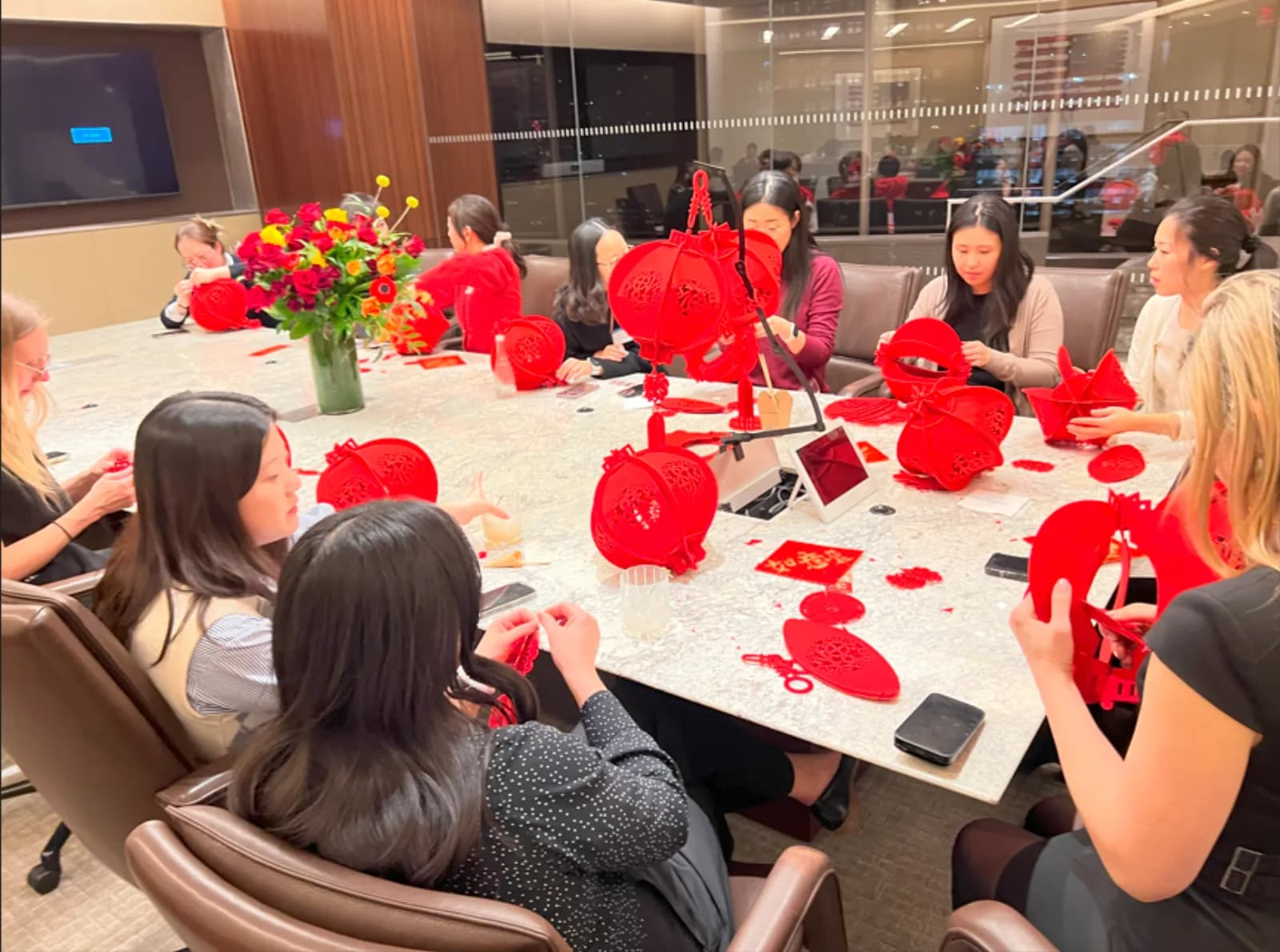 Coworkers assembling red lanterns together around a conference table at an office build a lantern station