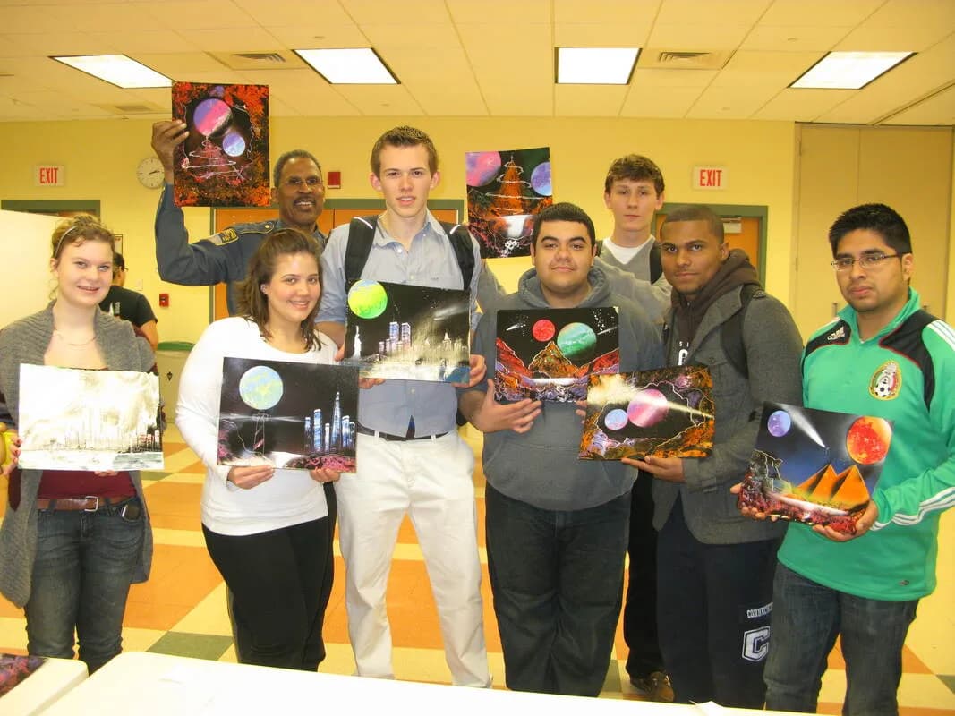 Guests posing with their finished spray paint canvas artwork at a live spray paint art station