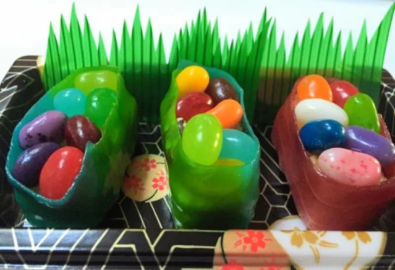 Candy sushi take-home boxes filled with colorful jelly beans styled like sushi rolls