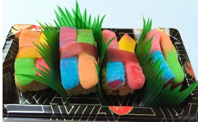 Colorful candy sushi rolls made from gummy candy and marshmallow, plated with decorative garnish