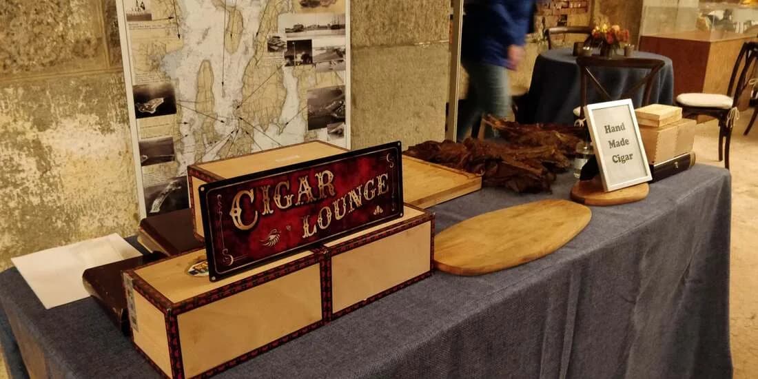 Vintage cigar lounge signage and dried tobacco leaves displayed at an upscale event cigar roller station