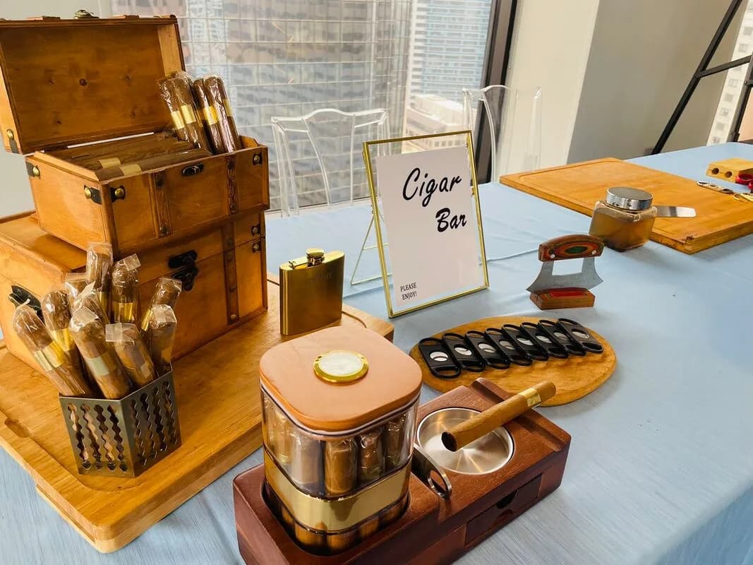 Cigar Bar table setup with humidor boxes, a flask, and cutters at an upscale event cigar roller station