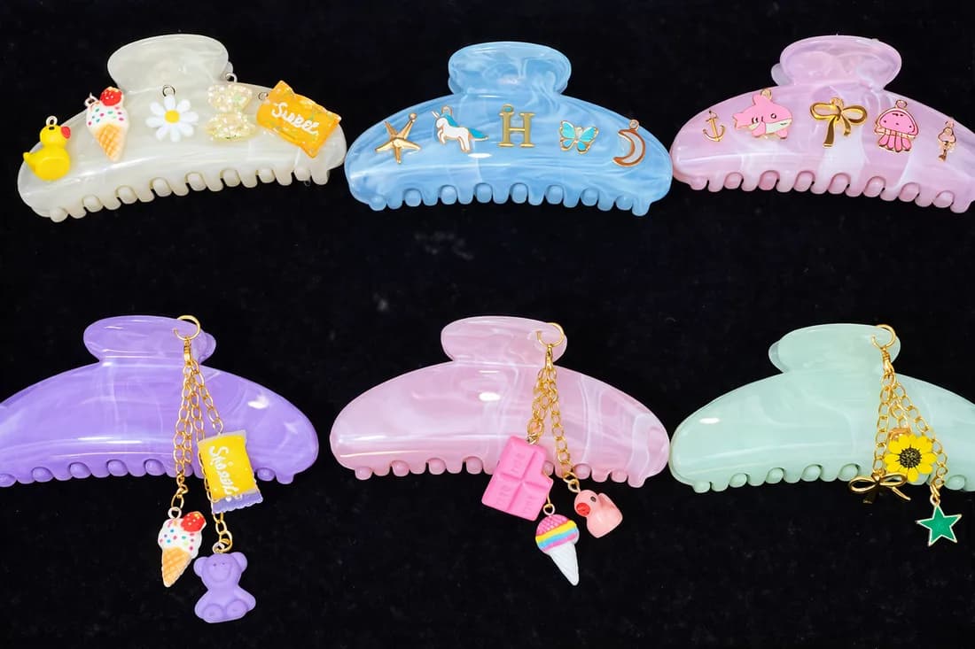 Assorted pastel claw clips decorated with charms including a duck, ice cream, and bow at an event claw clips bar