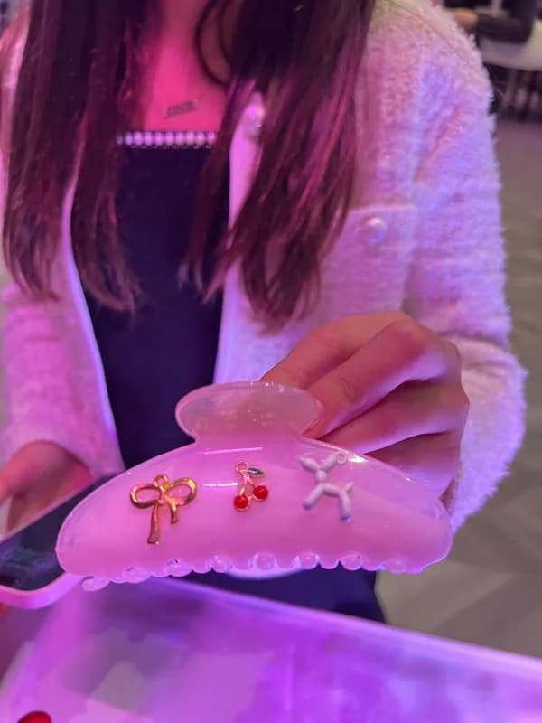 Guest holding a finished claw clip decorated with charms at an event claw clips bar station