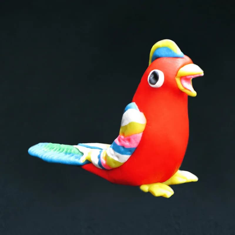 Handmade clay parrot sculpture in red, yellow, and blue, a finished piece from the clay sculptures station