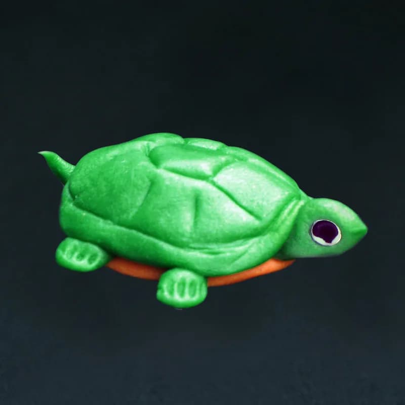 Handmade clay turtle sculpture in green and orange, a finished piece from the clay sculptures station