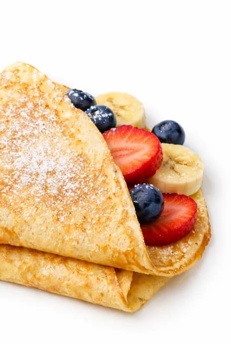 Folded crepe filled with fresh strawberries, blueberries, and banana at an event dessert station