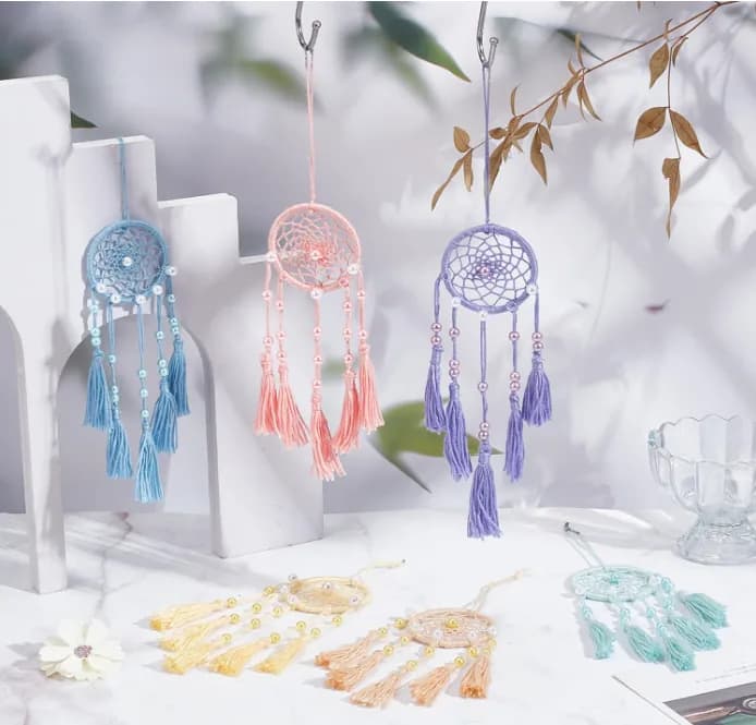 Three dream catchers in blue, pink, and purple thread hanging together with tassels and beads at a styled dream catcher display