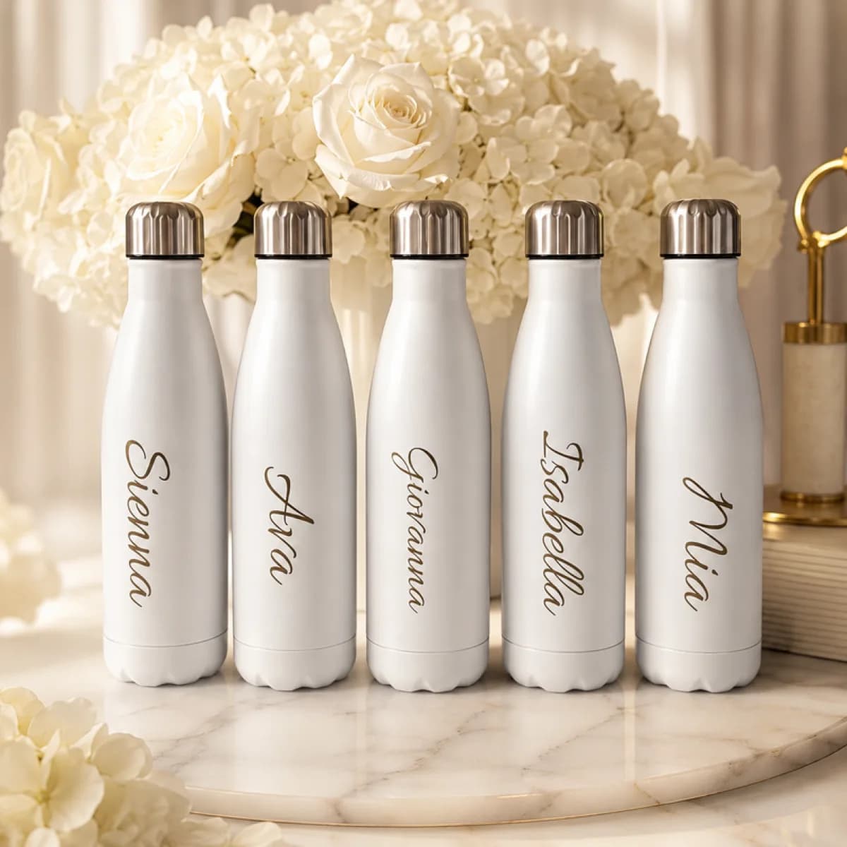 Personalized white water bottles engraved with guest names at an upscale event engraving station