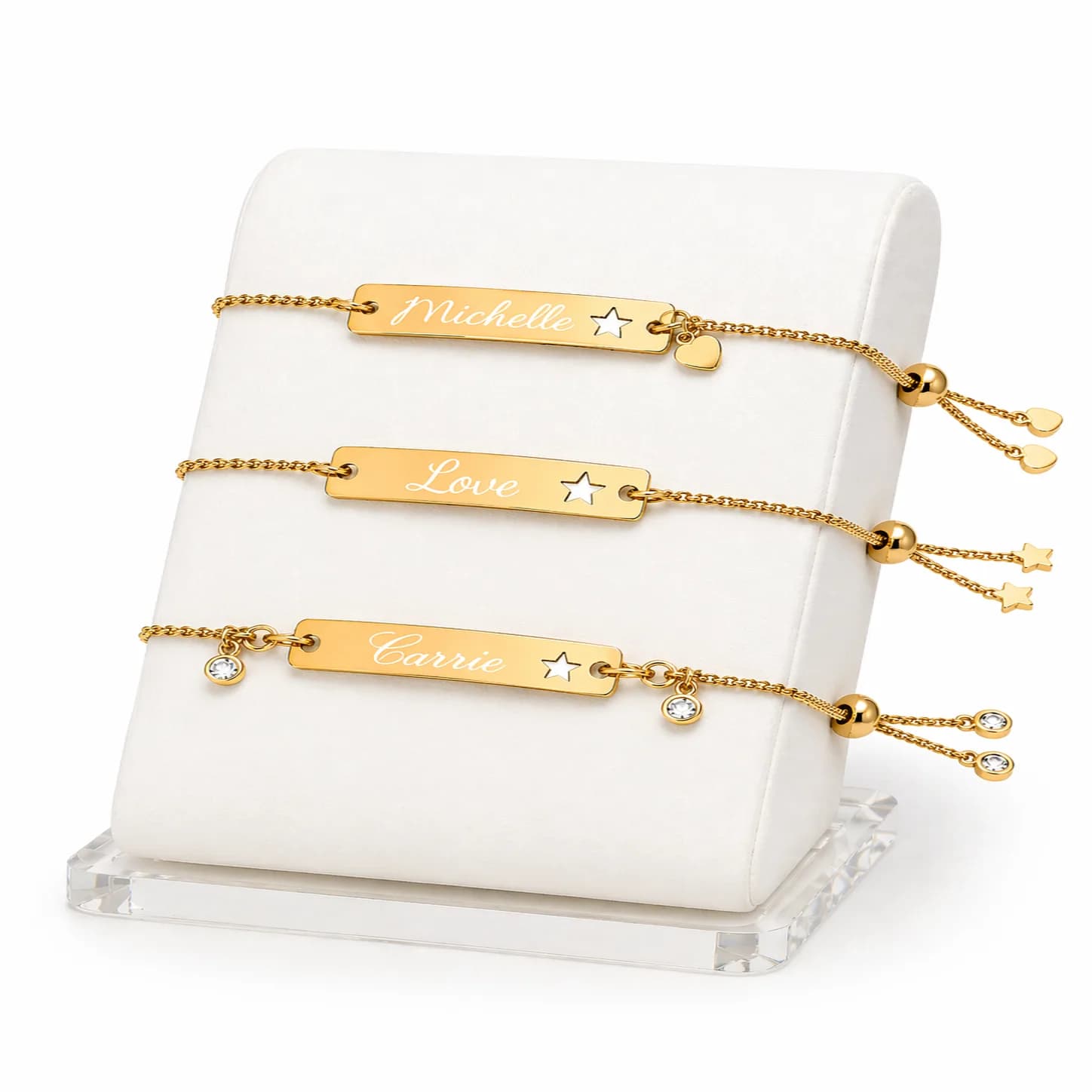 Gold bar bracelets engraved with three guest names displayed on a white velvet jewelry stand