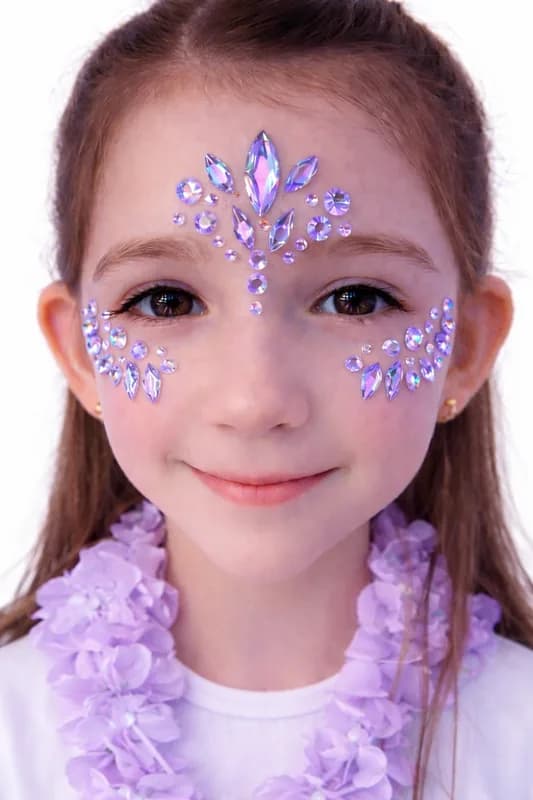 Young girl with a purple crystal face jewelry design and a flower lei at an event face jewelry station
