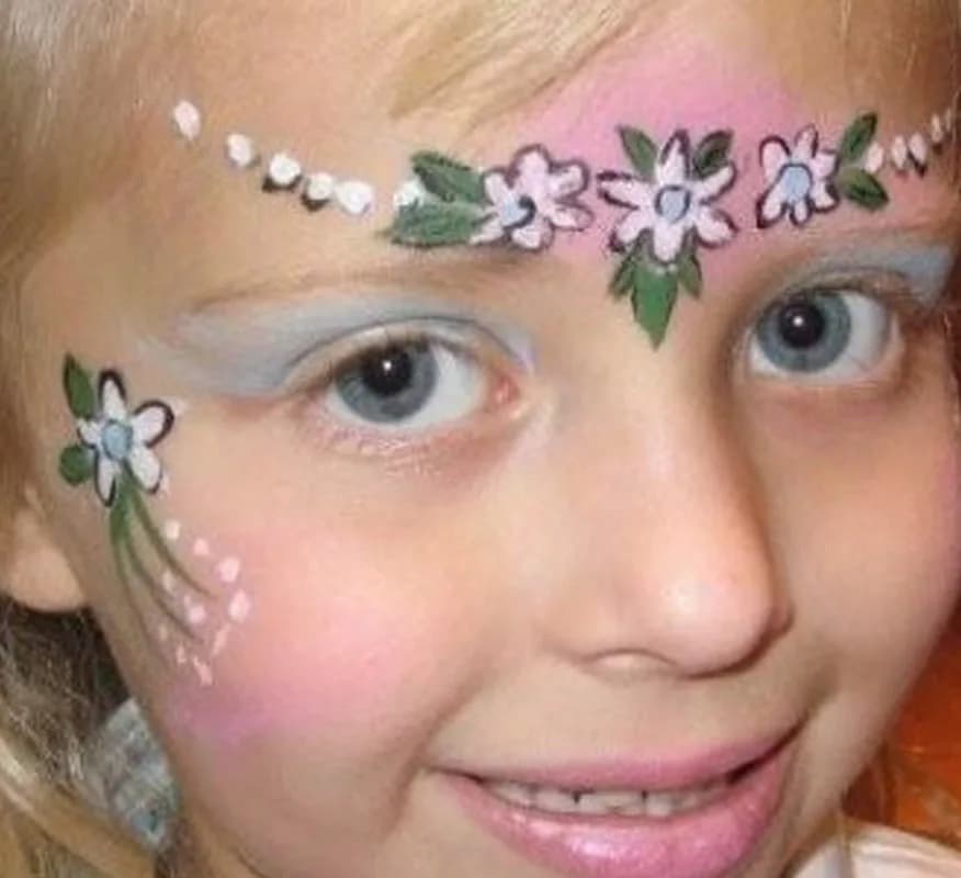 Close-up of a floral face painting design in pink, blue, and green across a child's brow and cheek