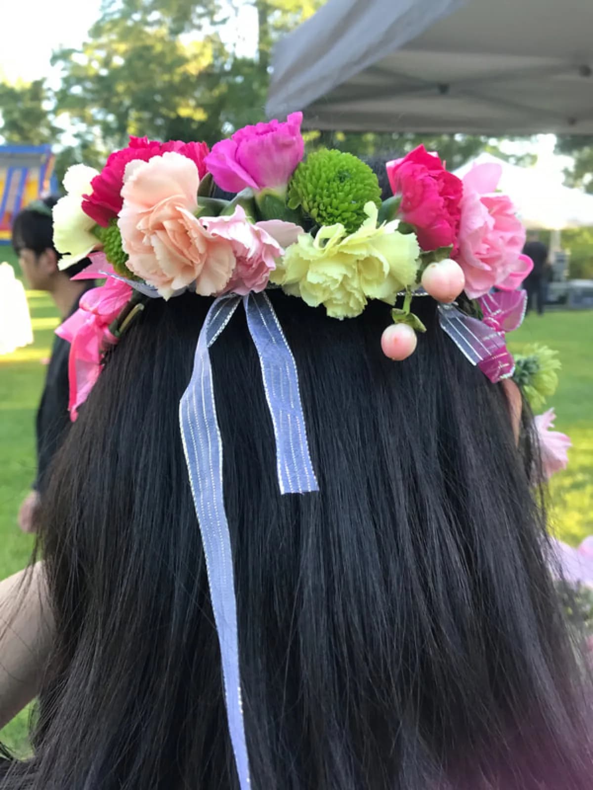 Guest wearing a finished flower crown with ribbon ties at an outdoor tented event