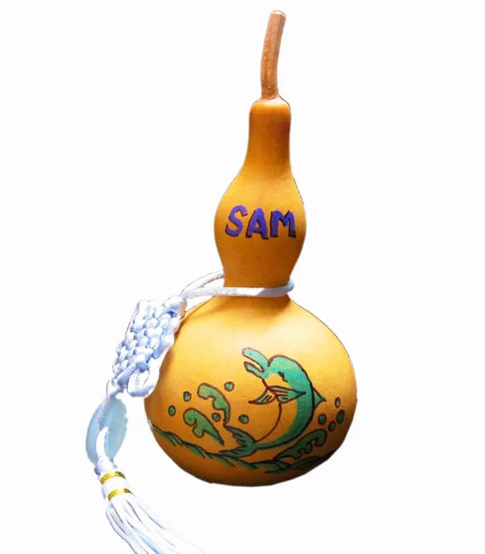 Hand-painted mini gourd charm with a dolphin and wave design and the name Sam, a keepsake from the good fortune keepsakes station