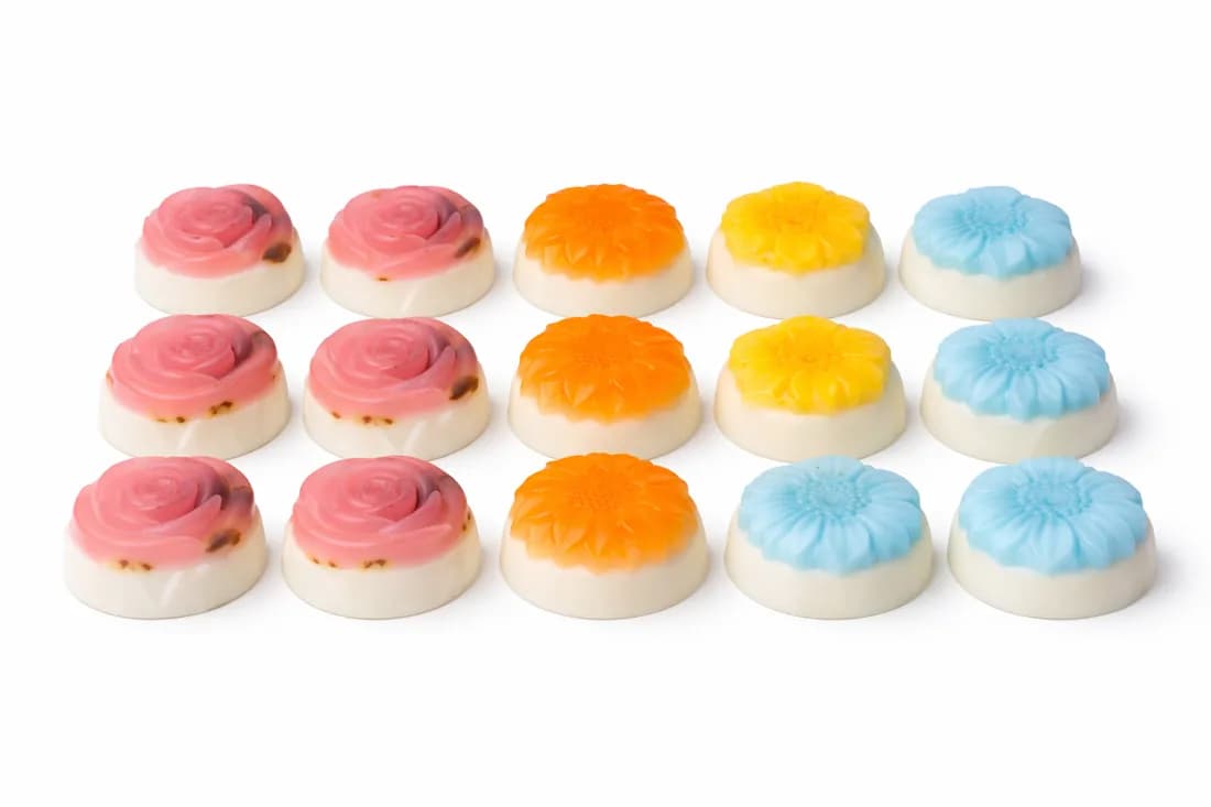 Rose, sunflower, and daisy shaped handmade soaps in pink, orange, yellow, and blue at a custom soap making station
