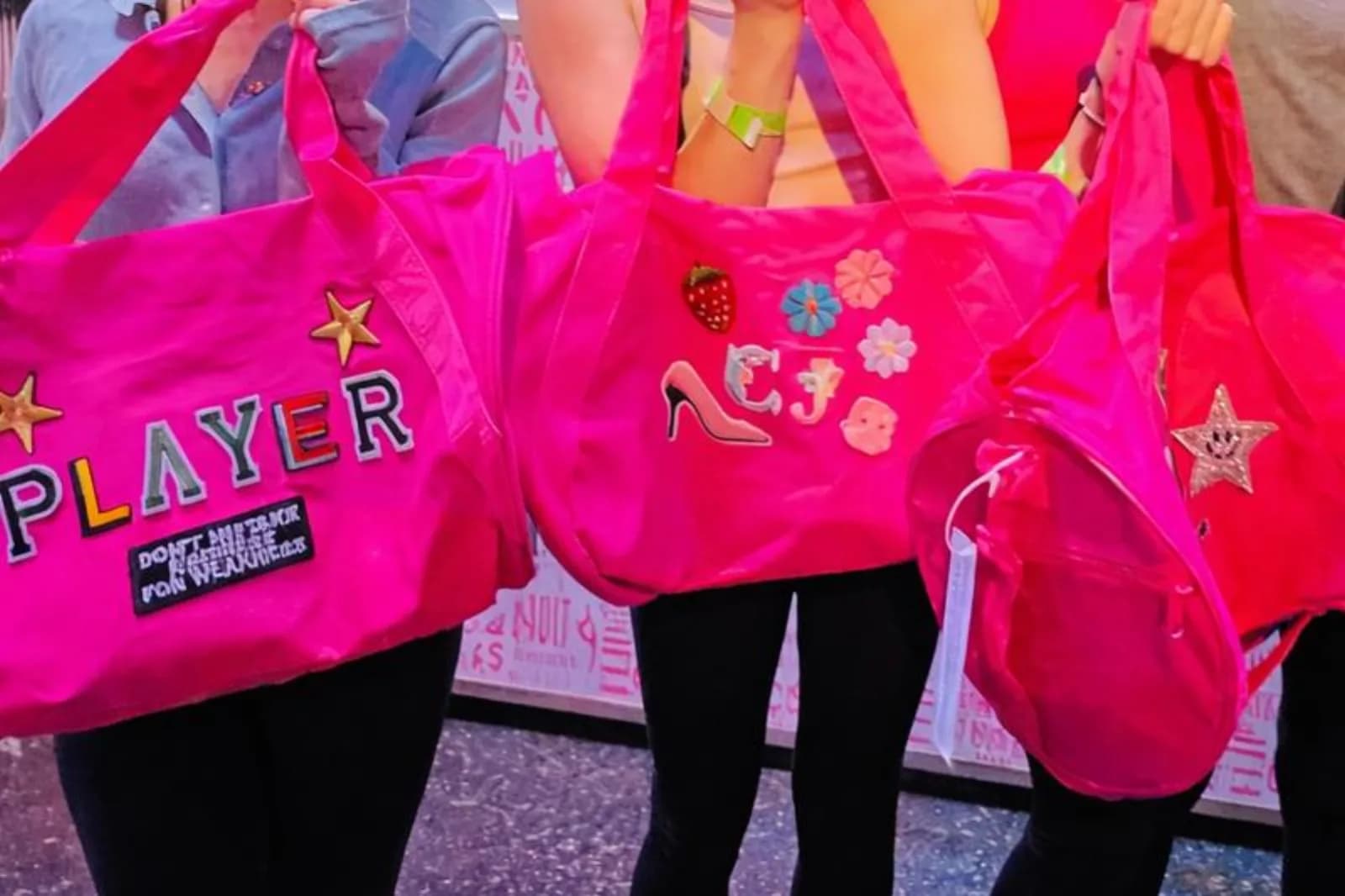 Guests holding pink tote bags customized with iron-on letter and flower patches from the iron patch station