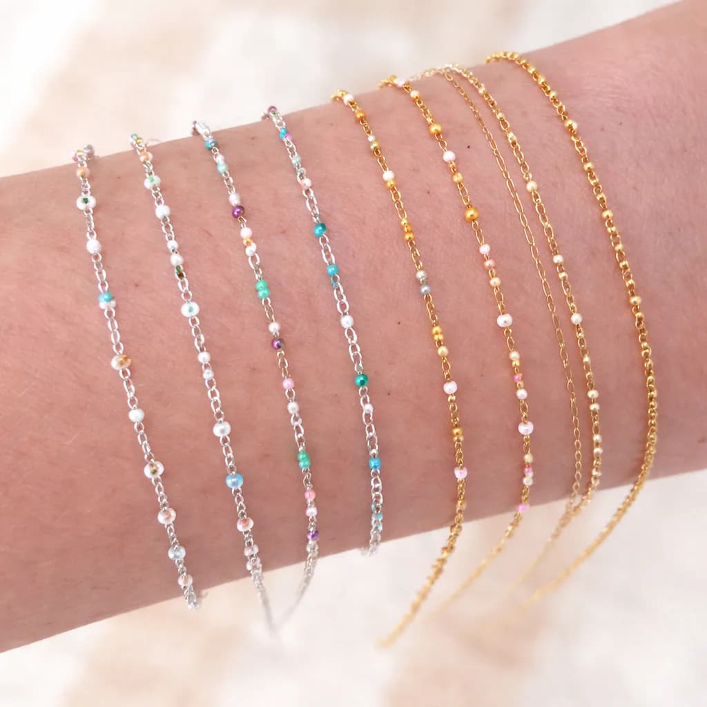 Close-up of layered gold and silver beaded bracelets stacked on a wrist from a jewelry station