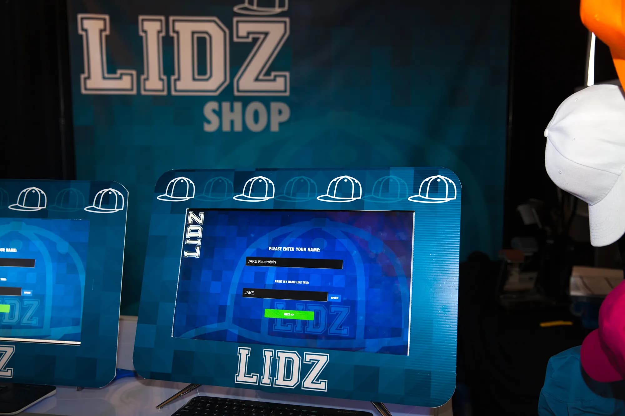 Custom hat kiosk close-up showing the touchscreen interface prompting a guest to enter their name for personalized embroidery
