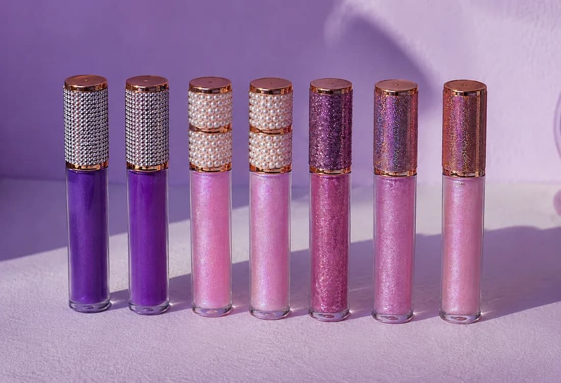 Row of finished lip gloss tubes in purple and pink shades with bedazzled caps at an event lip gloss bar