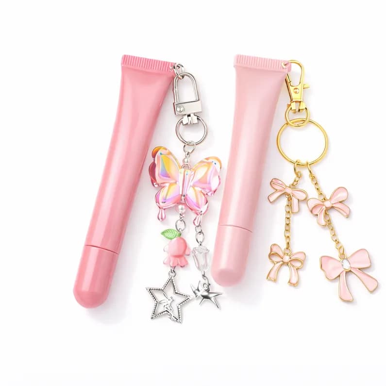 Two finished lip gloss tubes with butterfly and bow charm keychains, a take-home favor from the lip gloss bar