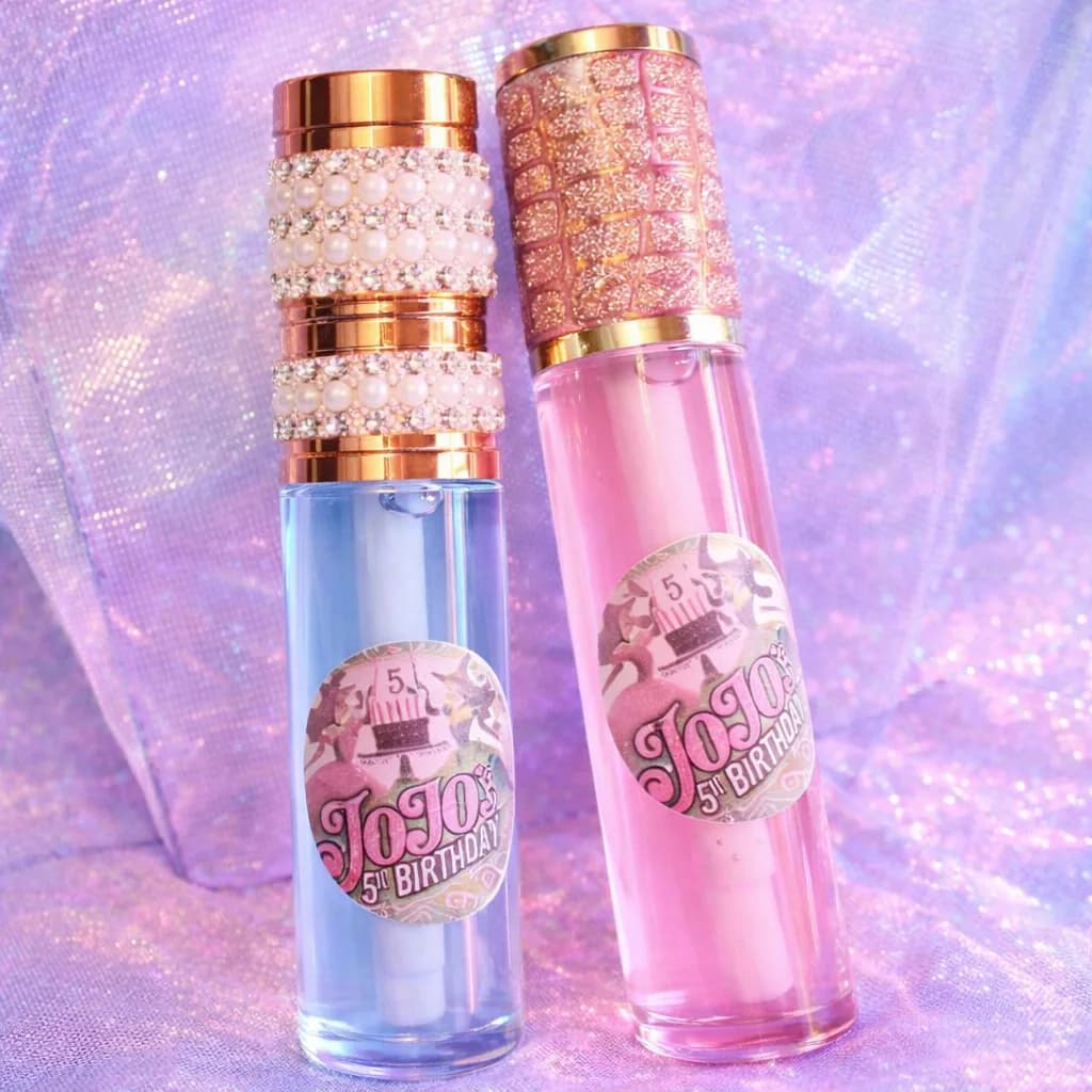 Two personalized lip gloss tubes with bedazzled pearl and rhinestone caps for a milestone birthday lip gloss bar