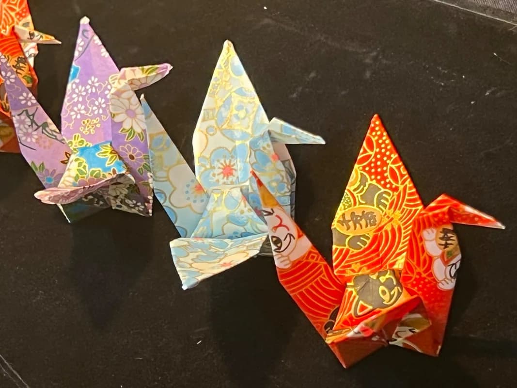 Row of folded origami cranes in purple, blue, and red patterned paper at the origami station