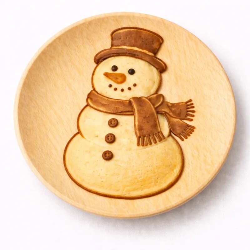 Pancake art shaped into a smiling snowman with a scarf for a winter-themed event