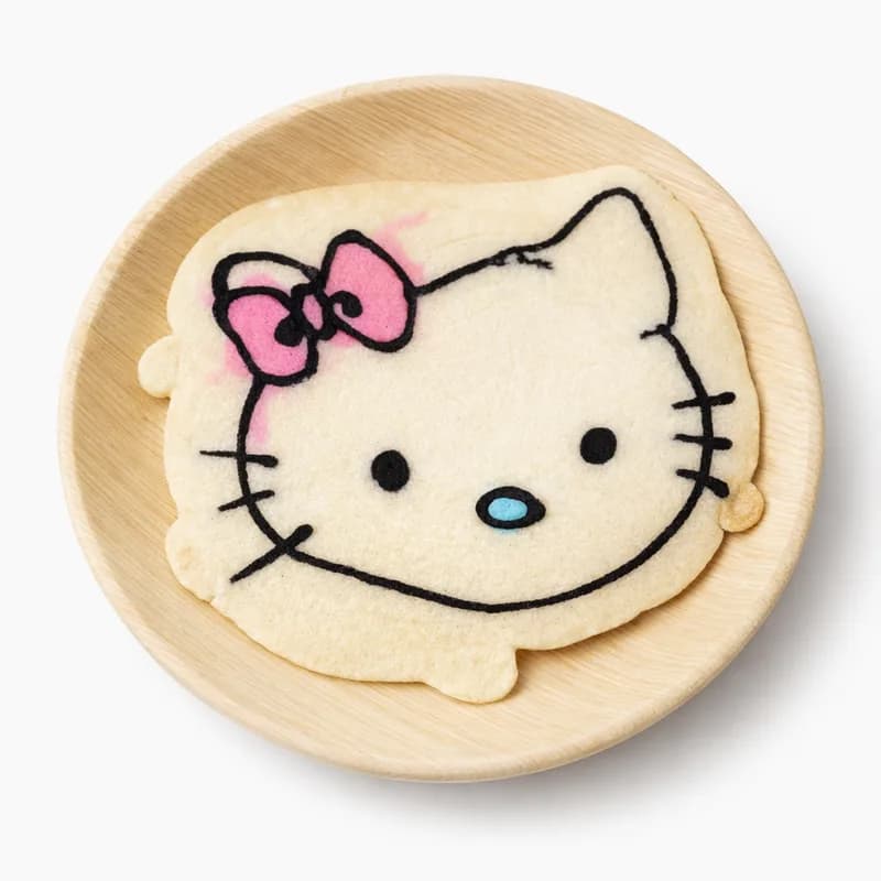 Pancake art shaped into a white cat character with a pink bow at a kids event pancake station