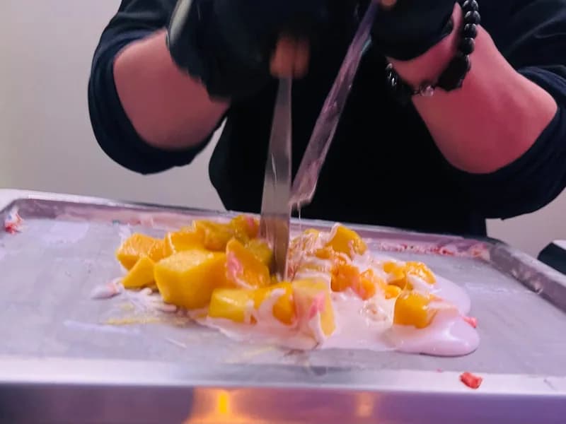 Fresh mango being chopped into the ice cream base on a frozen slab at an event station