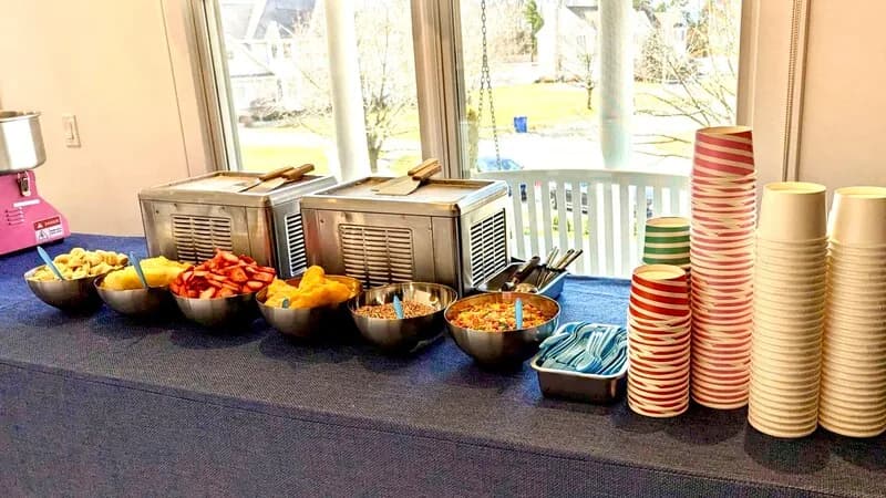 Rolled ice cream toppings bar with assorted mix-ins and cups at an event station