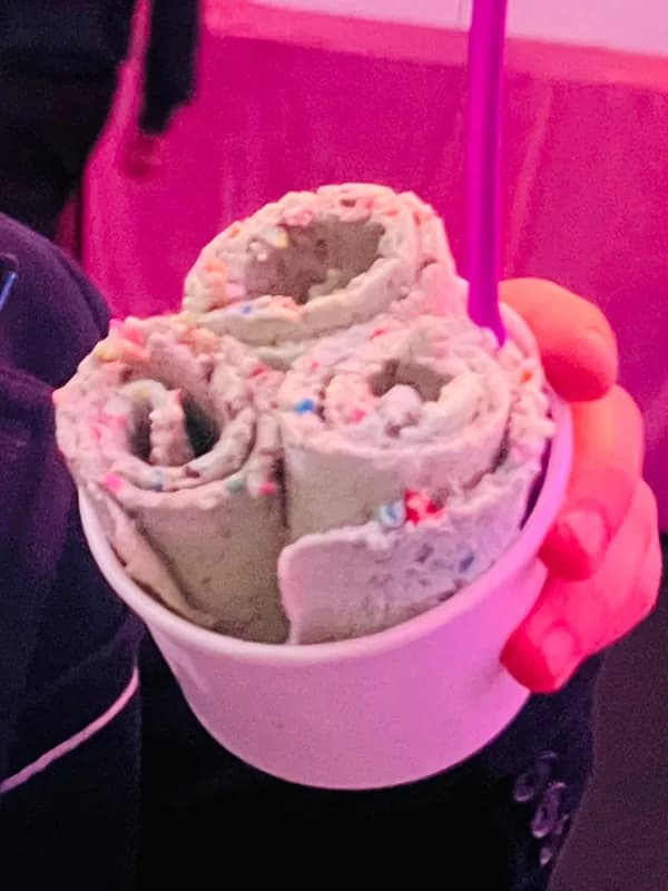 Finished cup of rolled ice cream with colorful sprinkle mix-ins held by a guest