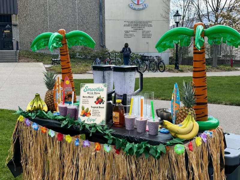 Tropical-themed smoothie bar station with inflatable palm trees and fresh fruit smoothies set up outdoors