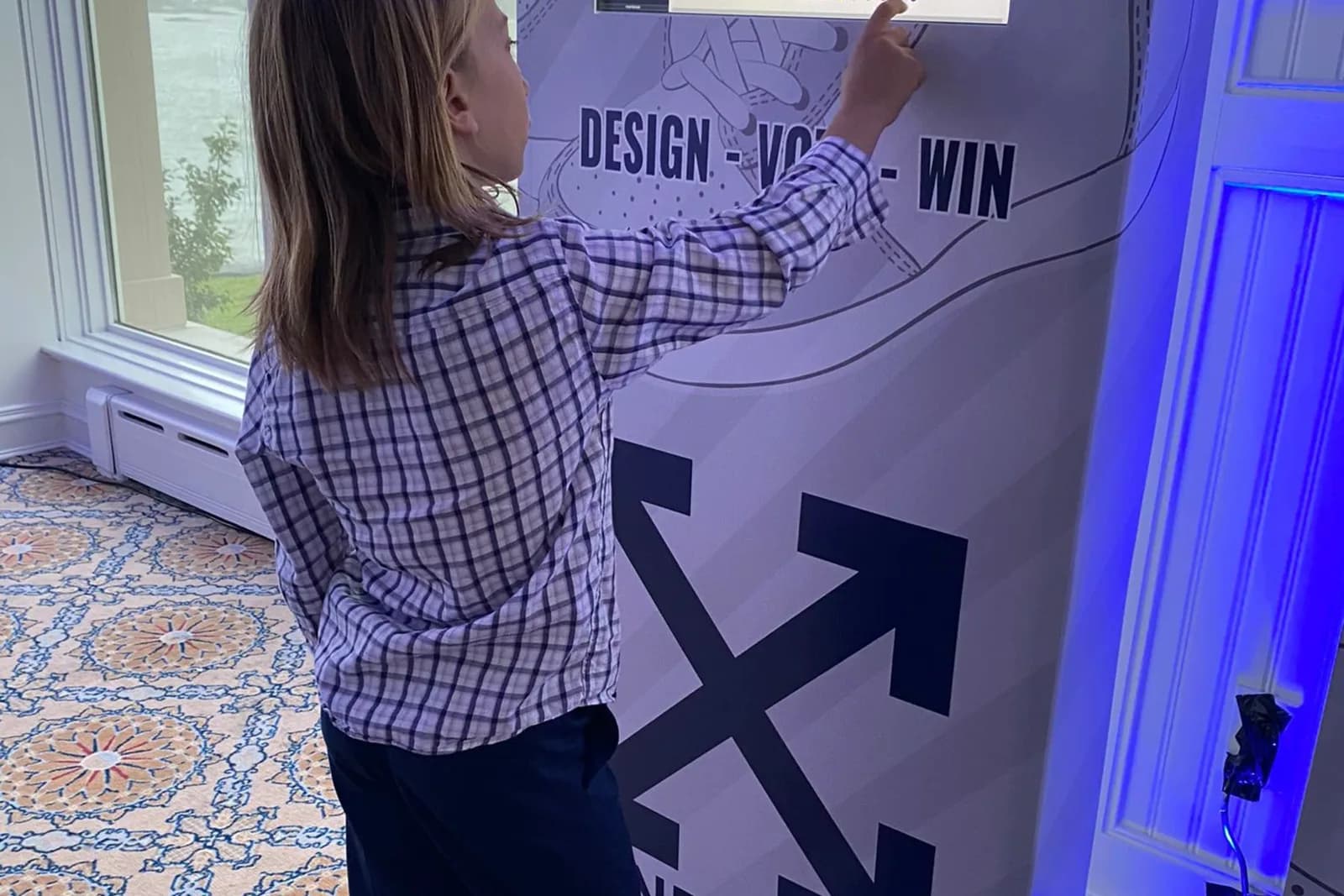 Guest pointing at a touchscreen kiosk to select a colorway while designing a custom sneaker