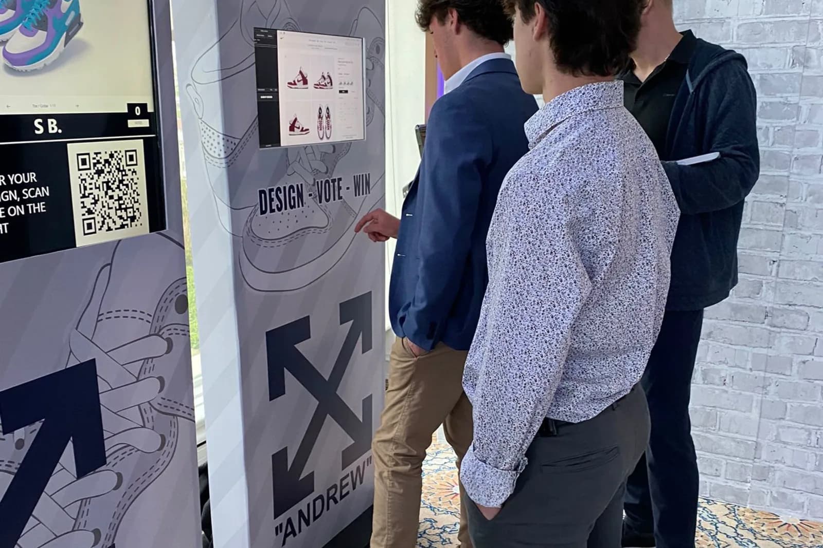 Group of guests gathered around a Sneaker Madness kiosk reviewing a custom sneaker design