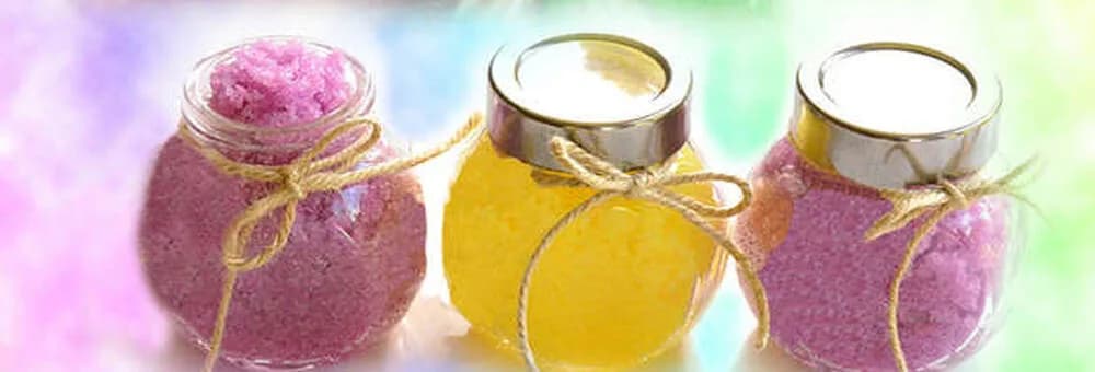 Trio of tied favor jars filled with pink, yellow, and purple sugar scrub, a take-home keepsake from the scrub station