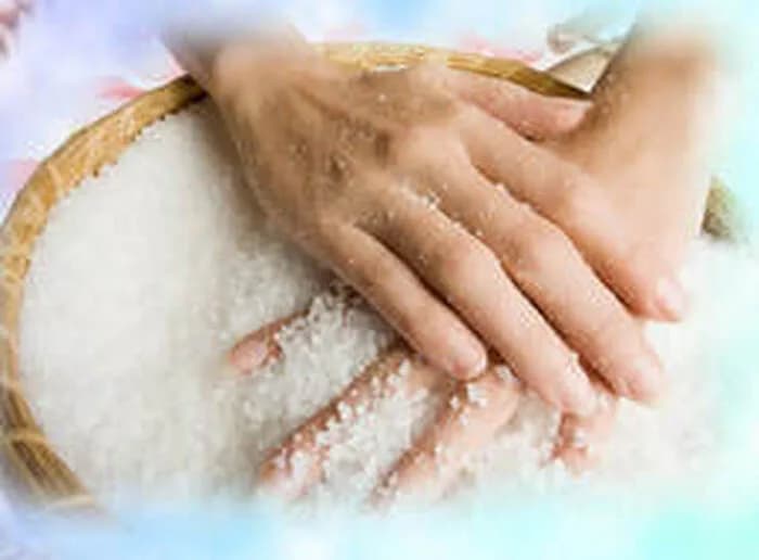 Guest scooping coarse salt by hand at the sugar and salt scrub station