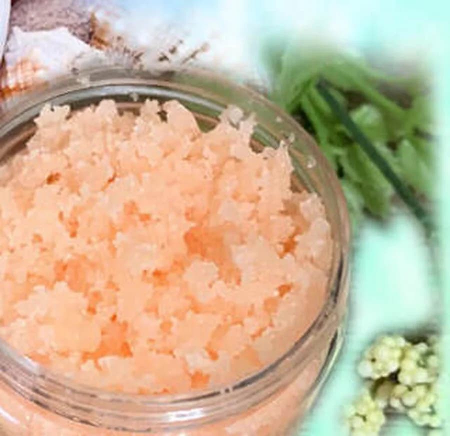 Jar of peach salt scrub displayed with fresh greenery, a finished favor from the sugar and salt scrub station