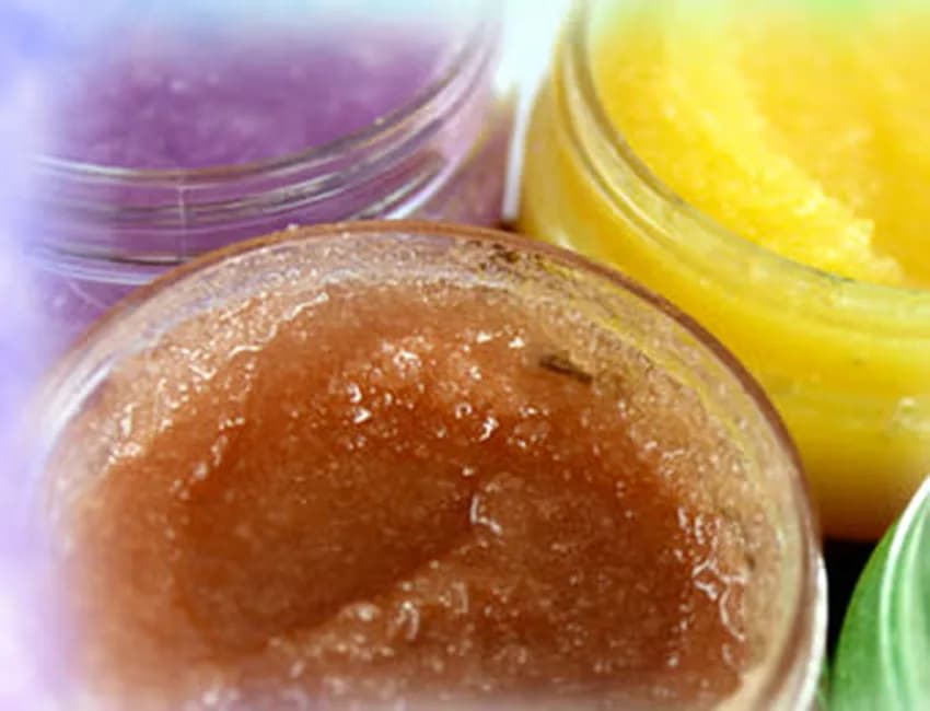 Overhead view of purple, brown, and yellow sugar scrub jars in a row, showing the color and texture choices at the sugar and salt scrub station