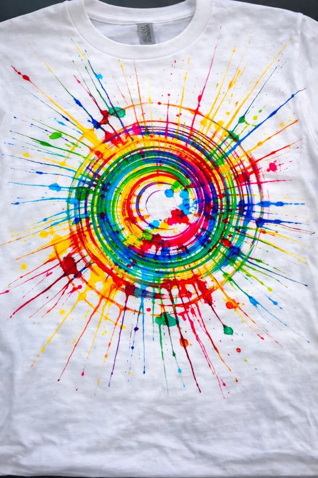 Close-up of a white t-shirt with a vibrant rainbow starburst spin art design