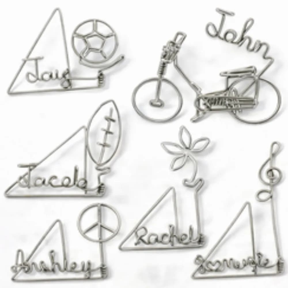 Assortment of custom wire art pieces including guest names, a bicycle, a soccer ball, and a peace sign at a wire art station
